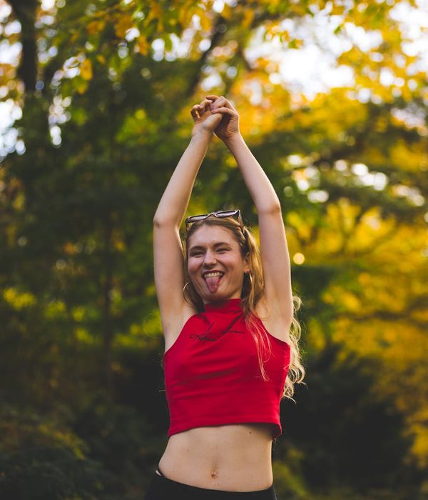 Woman smiling peacefully during a light stretching exercise outdoors.